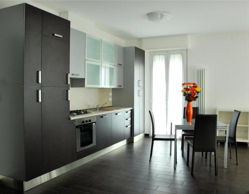 a kitchen with black cabinets and a table with chairs at Casa Vacanze Aurora Centro in Rimini