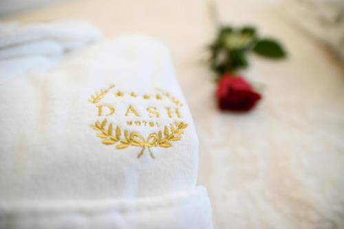 a white towel with a logo on it next to a plant at Garni Hotel Dash in Novi Sad