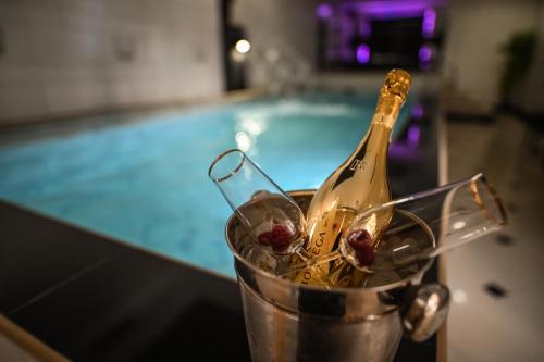 a bottle of champagne in a bucket next to a swimming pool at Garni Hotel Dash in Novi Sad