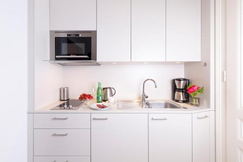 a white kitchen with a sink and a microwave at Pension Seehof Appartements in St. Wolfgang