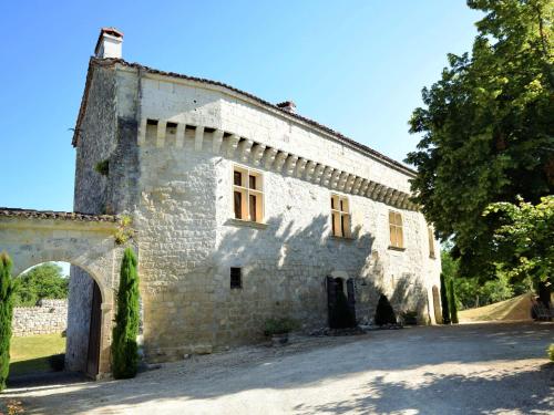 Saint-Caprais-de-LermにあるCastle 12th century with private pool close to Agenの庭のアーチ道のある古い石造りの建物