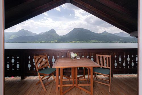 a table and chairs on a deck with a view of the water at Pension Seehof Appartements in St. Wolfgang