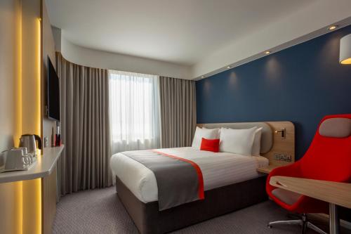 um quarto de hotel com uma cama e uma cadeira vermelha em Holiday Inn Express - Barrow-in-Furness & South Lakes, an IHG Hotel em Barrow in Furness