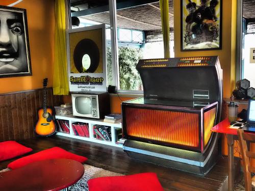 a living room with a tv and a guitar at Sunflower Beach Backpacker Hostel in Rimini