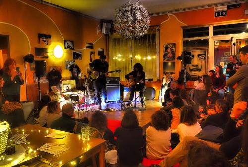 a group of people sitting in a room with a band at Sunflower Beach Backpacker Hostel & Bar in Rimini
