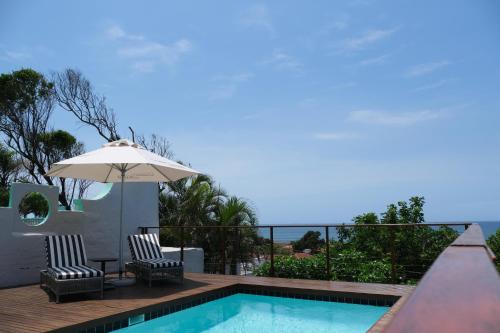a swimming pool with two chairs and an umbrella at Ocean Vista Boutique Guest House in Durban