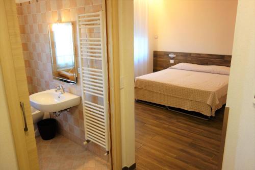 a small bathroom with a bed and a sink at Euromotel Croce Bianca in Verona