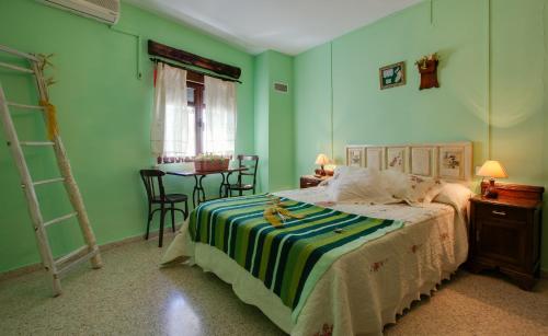 - une chambre avec des murs verts et un lit avec une couverture rayée dans l'établissement Casa Rural Abuela Maxi, à Ríolobos