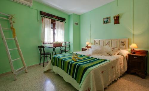 1 dormitorio con paredes verdes y 1 cama con manta a rayas en Casa Rural Abuela Maxi, en Riolobos