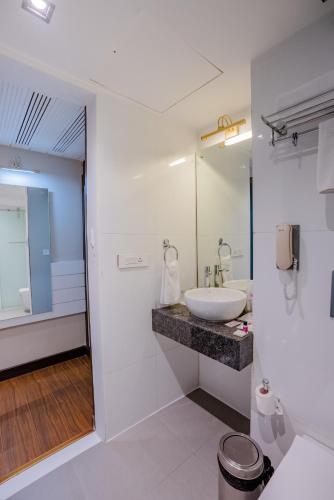 a white bathroom with a sink and a mirror at Regenta Inn Jaipur, Adarsh Nagar in Jaipur