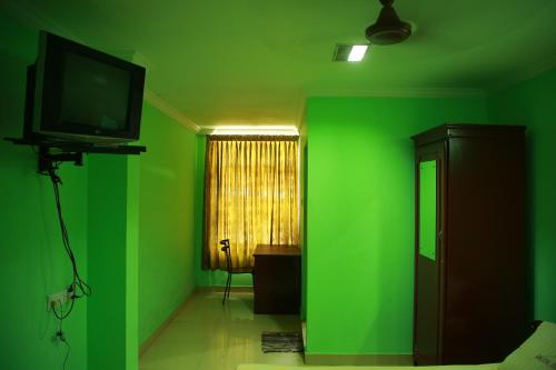une salle verte avec une télévision et un mur vert dans l'établissement KALATHIL TOURIST HOME, à Kunnamkulam