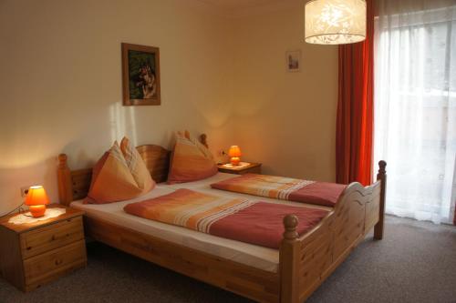 een slaapkamer met een houten bed en 2 lampen op tafels bij Appartementhaus Alpina in Flattach