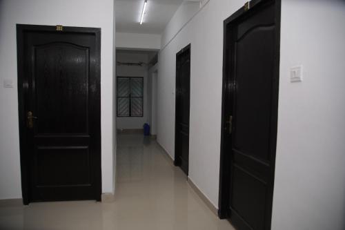 a hallway with two black doors and a white wall at MEGHNA RESIDENCY in Trivandrum