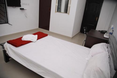 a bedroom with a bed with white sheets and a red blanket at MEGHNA RESIDENCY in Trivandrum
