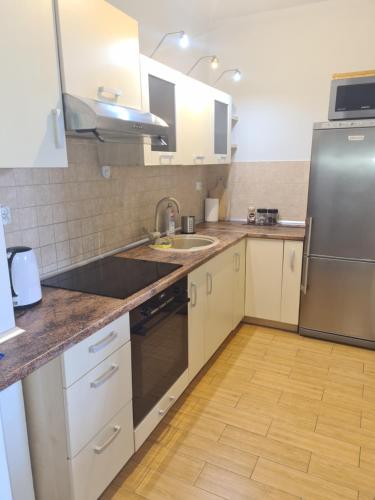 a kitchen with white cabinets and a stainless steel refrigerator at Apartament z garażem podziemnym - Augustowska in Olsztyn