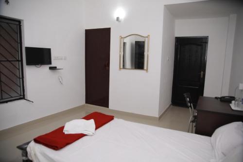 a bedroom with a white bed with a red towel on it at MEGHNA RESIDENCY in Trivandrum