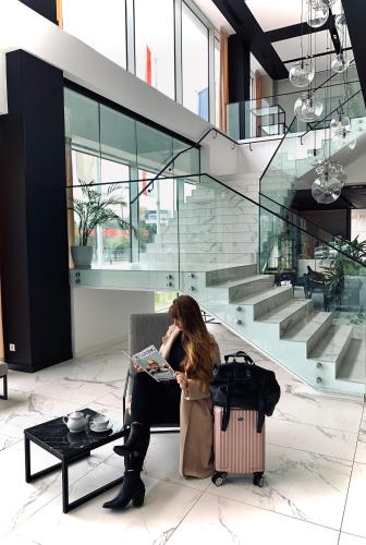 a woman sitting on a chair reading a magazine at Arche Hotel Krakowska in Warsaw