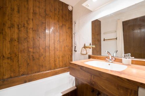 La salle de bains est pourvue d'un lavabo et d'un mur en bois. dans l'établissement L'Etoile de Megeve, à Megève