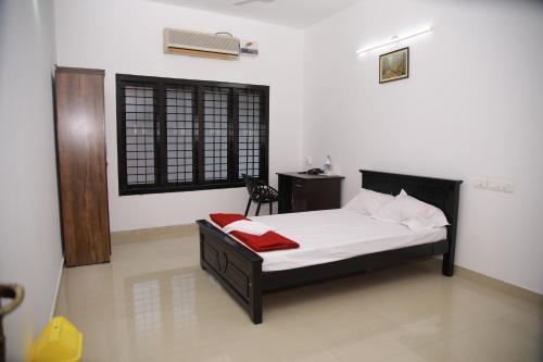 a bedroom with a bed with a red blanket on it at MEGHNA RESIDENCY in Trivandrum