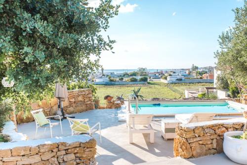 a backyard with a pool and chairs and a stone wall at Villa il Cristallo - Homelike Villas in Torricella