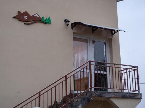 a building with a balcony and a door with a house sign at ȘURA LU' PĂTRU in Vulcan