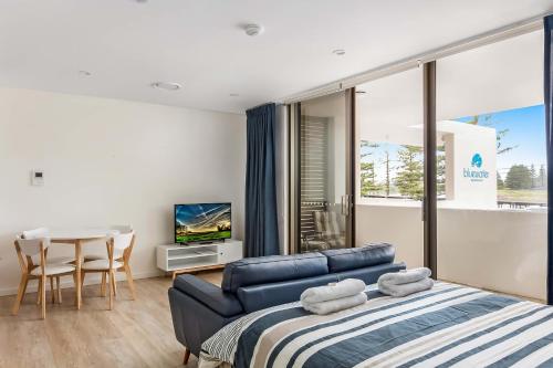 a bedroom with a couch and a table with a tv at Bluewater Apartments in Kiama