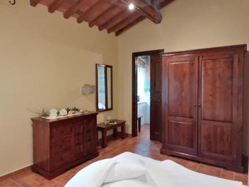 a bedroom with a wooden cabinet and a mirror at Tenuta Seripa in Sassetta
