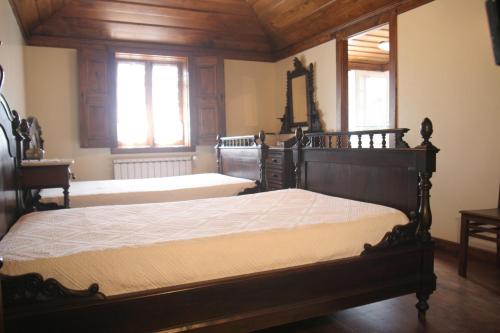 a bedroom with two beds with wooden floors and windows at Casa De Carcavelos in Cabeceiras de Basto
