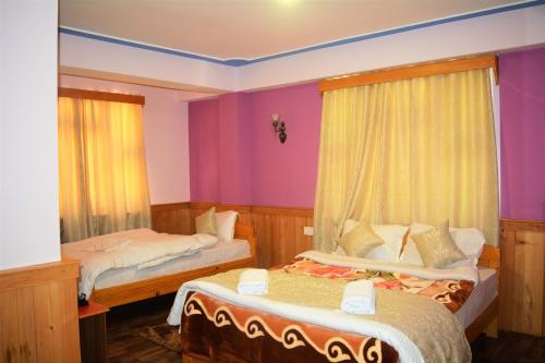two beds in a room with purple walls at Rufina Lachung de'CROWN in Lachung