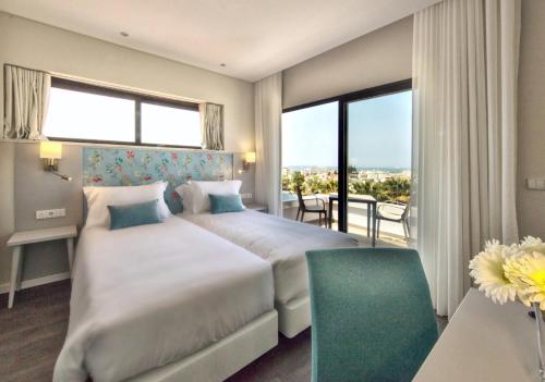een hotelkamer met 2 bedden en een balkon bij Agua Hotels Alvor Jardim in Alvor