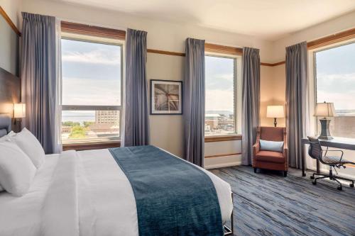 um quarto de hotel com uma cama, uma secretária e janelas em The Courthouse Hotel, Ascend Hotel Collection em Thunder Bay