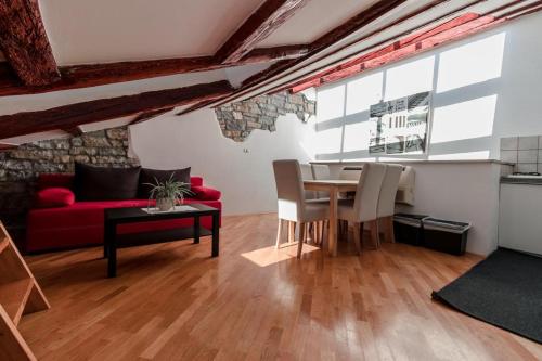 a living room with a table and a red couch at Apartments Artemus Music in Piran