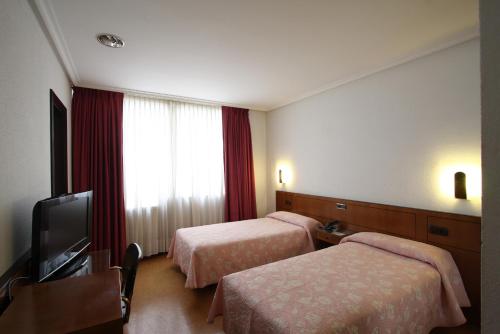 a hotel room with two beds and a flat screen tv at Santacruz in Oviedo