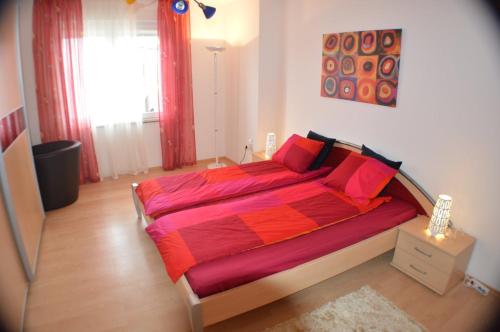 1 dormitorio con 1 cama grande con sábanas rojas en Holiday apartment in house Damir en Sveti Filip i Jakov