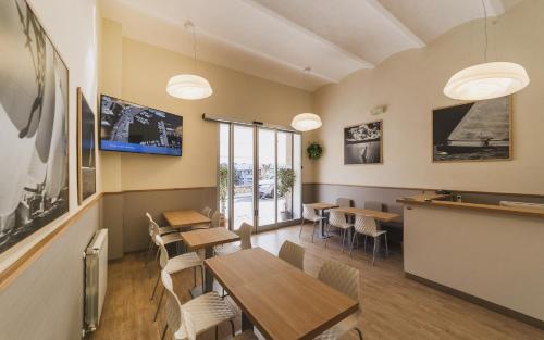 un restaurante con mesas y sillas de madera y ventanas en Hotel Alfiero en Porto Santo Stefano