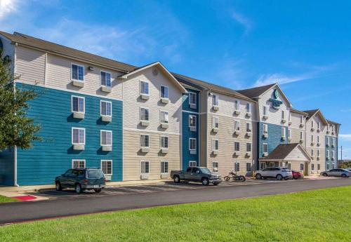 a large apartment building with cars parked in a parking lot at WoodSpring Suites Houston Baytown in Baytown