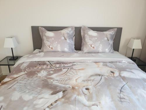 a bed with a white comforter and two lamps at Snooze in Ostend