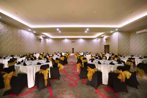 a banquet hall with white tables and yellow bows at favehotel PGC Cililitan in Jakarta