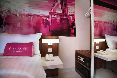 a bedroom with a bed with a pink wall at favehotel PGC Cililitan in Jakarta
