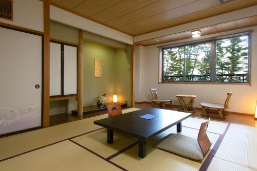 a living room with a table and chairs and a window at Hamabeno Ryouriyado Houraikan in Kamaishi
