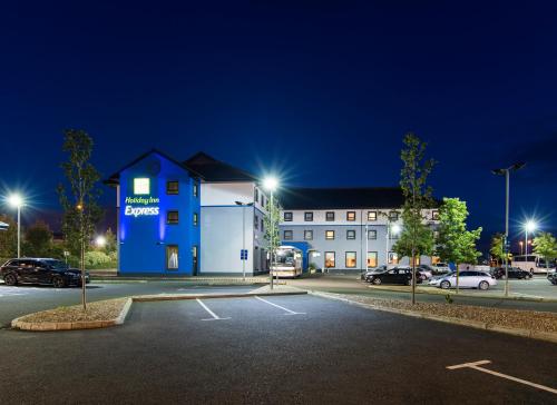 a building with a parking lot in front of it at Holiday Inn Express Antrim by IHG in Antrim