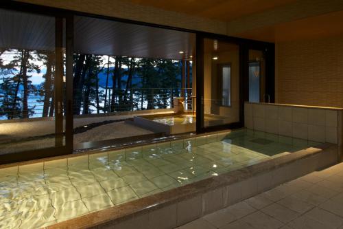 a jacuzzi tub in a building with windows at Hamabeno Ryouriyado Houraikan in Kamaishi