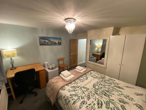 a bedroom with a bed and a desk and a mirror at Prince Cottage in Colchester