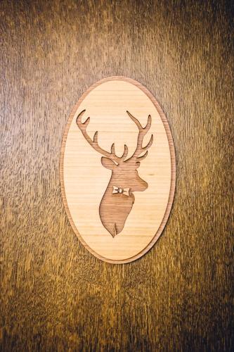 a wooden plate with a deer head on a table at Natur Hotel Kövestető in Hosszúhétény
