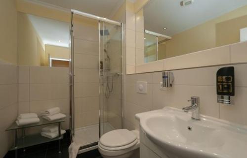 a bathroom with a shower and a toilet and a sink at Hotel Grüne Tanne in Hamburg