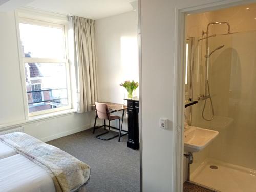 アムステルダムにあるホテル ヴェルディのベッド、洗面台、バスルームが備わるホテルルームです。