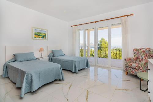 a bedroom with two beds and a chair and a window at Villa Quiros 2 in El Port