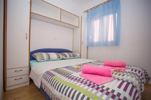 a bedroom with a bed with pink pillows on it at Apartments Mala Karla 1685 in Seget Vranjica
