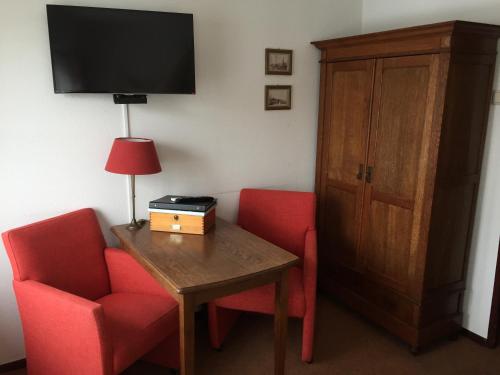 a room with two red chairs and a table and a television at Hanzestadslogement "De Leeuw", logies in het centrum van Deventer in Deventer