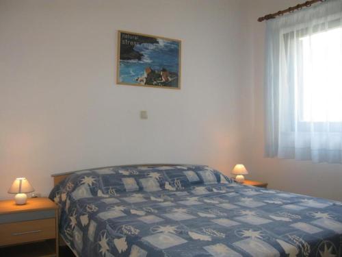 a bedroom with a bed with a blue and white comforter at Apartments Pende 3122 in Banjol